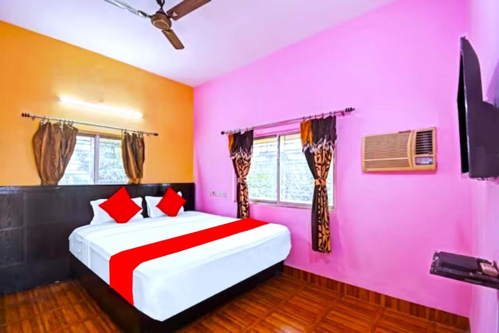 um quarto com paredes cor-de-rosa e uma cama com almofadas vermelhas em Goroomgo Salt Lake Palace Kolkata - Fully Air Conditioned & Parking Facilities em kolkata