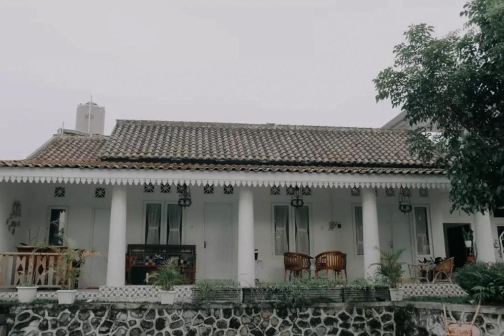 une maison blanche avec un mur en pierre dans l'établissement Villa Omah Dpartos, à Sleman