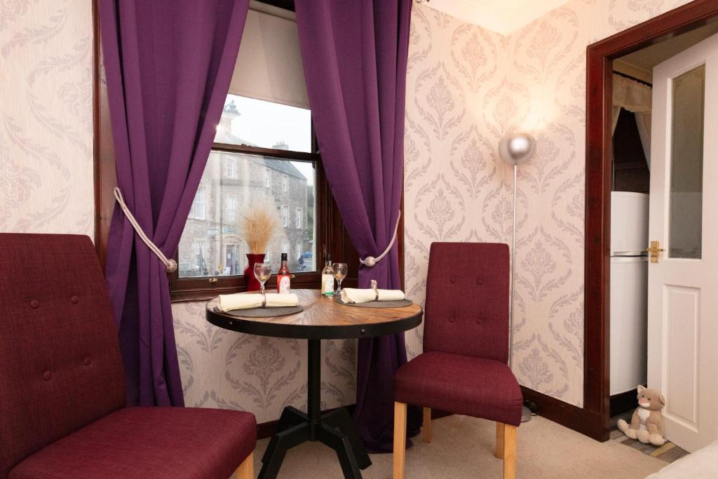 uma mesa e duas cadeiras num quarto com cortinas roxas em Hawick Haven em Hawick