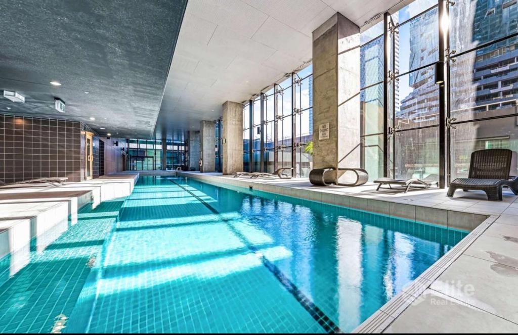 een groot zwembad met blauw water in een gebouw bij 2BR & Balcony - Pool & GYM - Train Station - 3 min in Melbourne