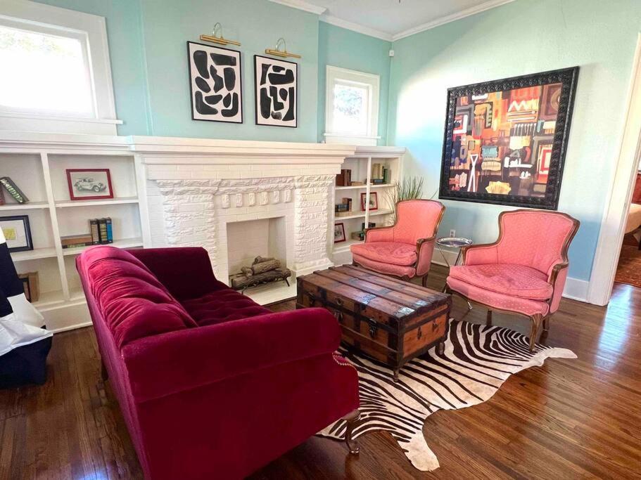 a living room with two red chairs and a fireplace at Blue Bungalow near OU Med/Downtown in Oklahoma City