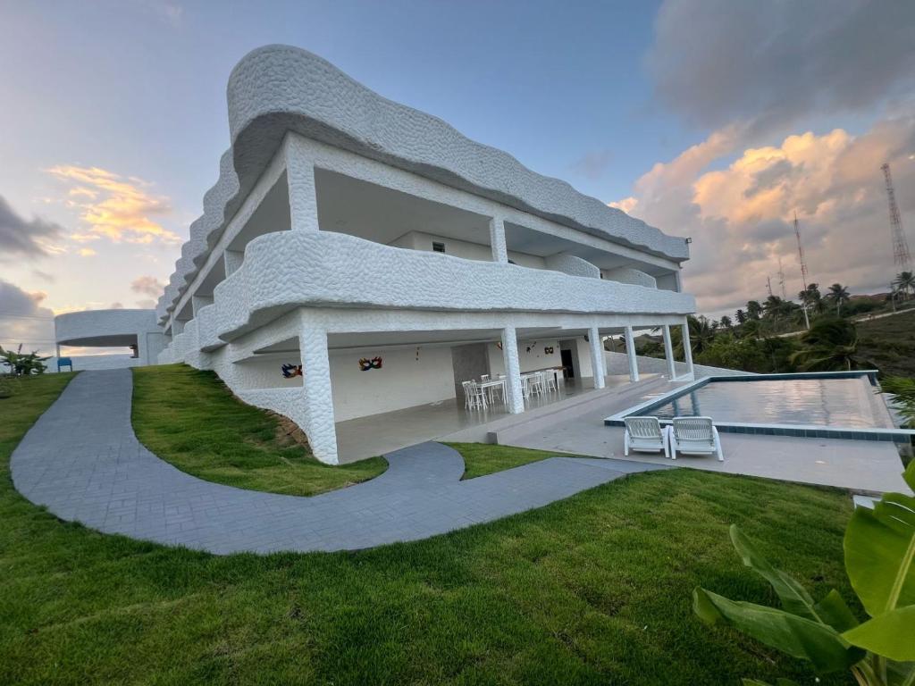 uma casa branca com uma piscina no quintal em KEFI POUSADA em Maragogi