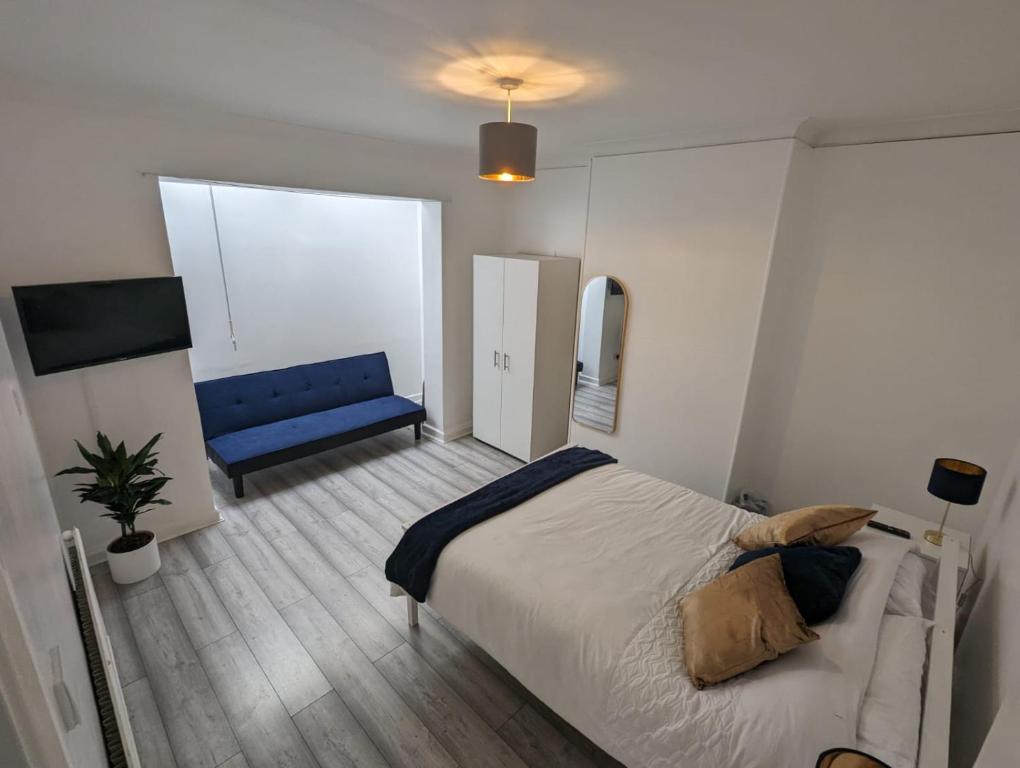 een slaapkamer met een bed en een blauwe bank bij The Manor Guest House in Wembley in Londen