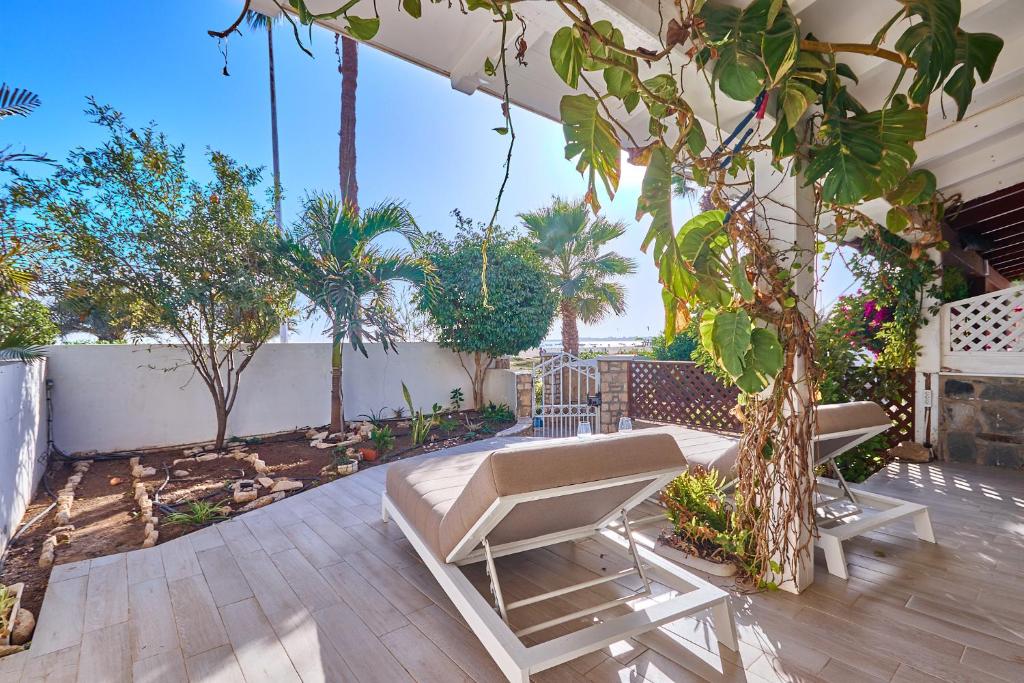 a patio with two chairs and a tree at Beach Villa by Bobbywashere in Santa Maria