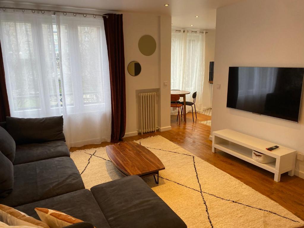 un salon avec un canapé et une télévision à écran plat dans l'établissement Un nid douillet- parking privé-résidence fermée-45m2, à Aubervilliers