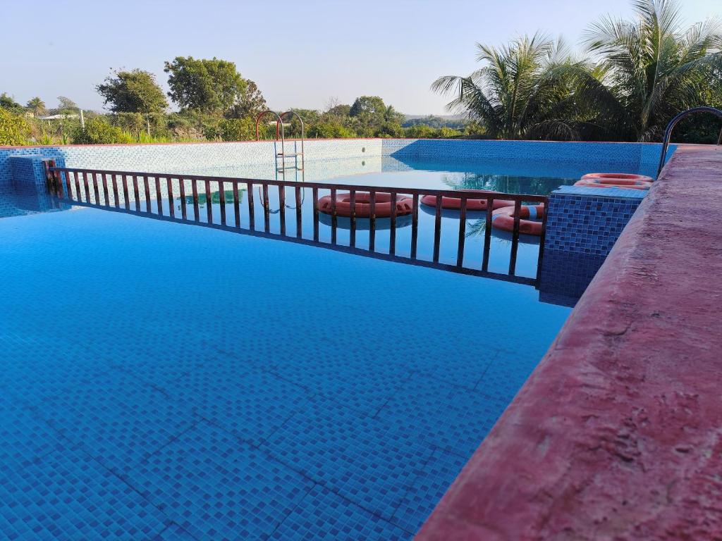 a swimming pool with blue water and a fence at Gokul farm house in Sasan Gir