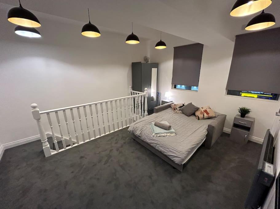 a bedroom with a bed and a staircase with lights at City Studio Escape near Emirates in London