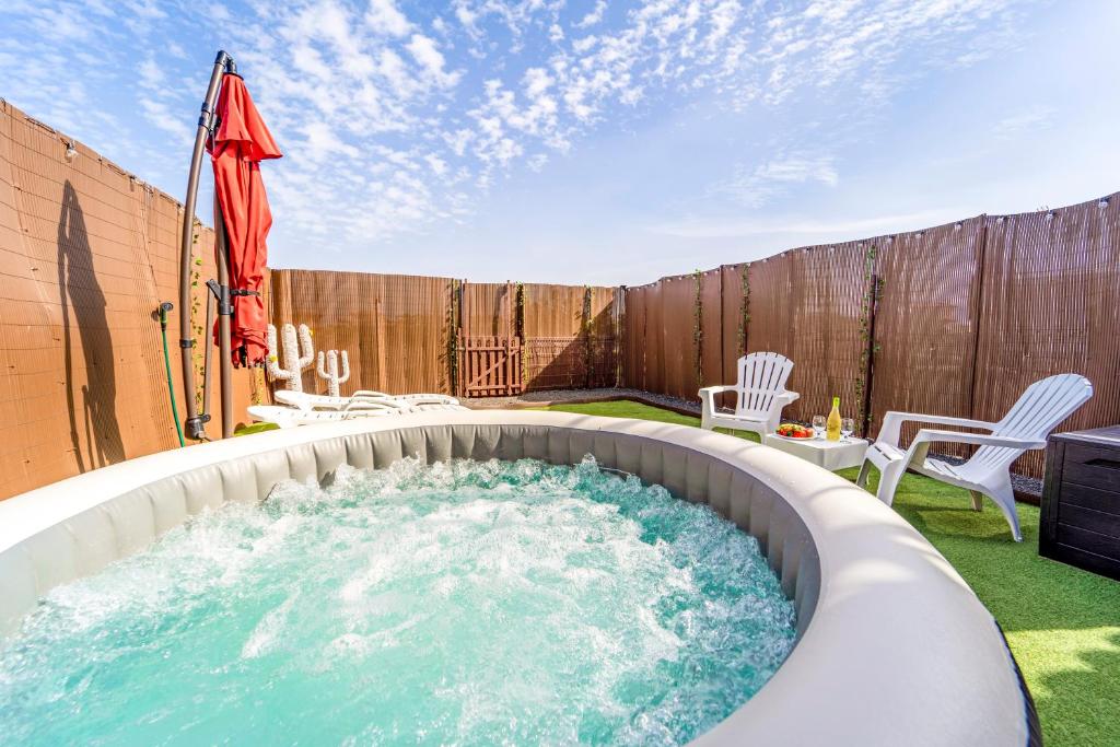 a hot tub in a backyard with chairs and an umbrella at Villa Colibri Dorado in Lajares