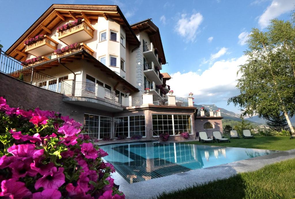 a house with a swimming pool and flowers at Hotel Lagorai Resort & Spa in Cavalese