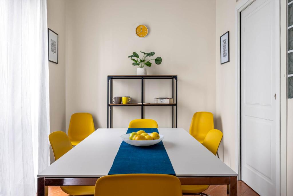 uma mesa de jantar com cadeiras amarelas e uma taça de fruta em Sedie Volanti Apartment with Jacuzzi em Palermo