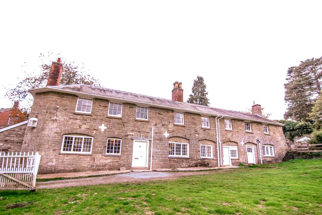 un antiguo edificio de ladrillo con una puerta blanca en un campo de césped en Garden House, en North Lydbury