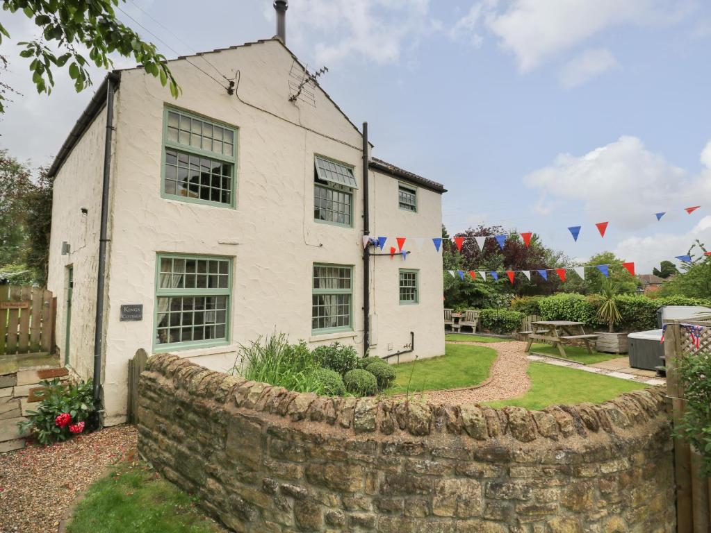 a white house with a stone fence in front of it at King's Cottage in Bedale