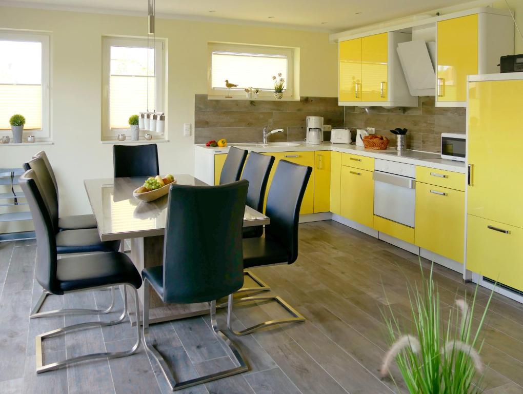 cocina con armarios amarillos, mesa y sillas en Ferienhaus Lachmöwe, en Fehmarn