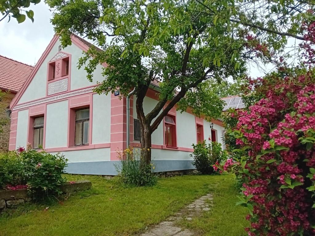 a pink and white house with a tree in the yard at Chalupa Baroko in Mojné