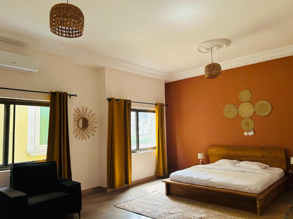 a bedroom with a bed and a chair and a window at Cocoon Guest House in Cotonou