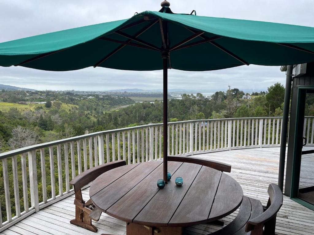 una mesa de madera con una sombrilla en la cubierta en Peaceful and close to town, en Whangarei