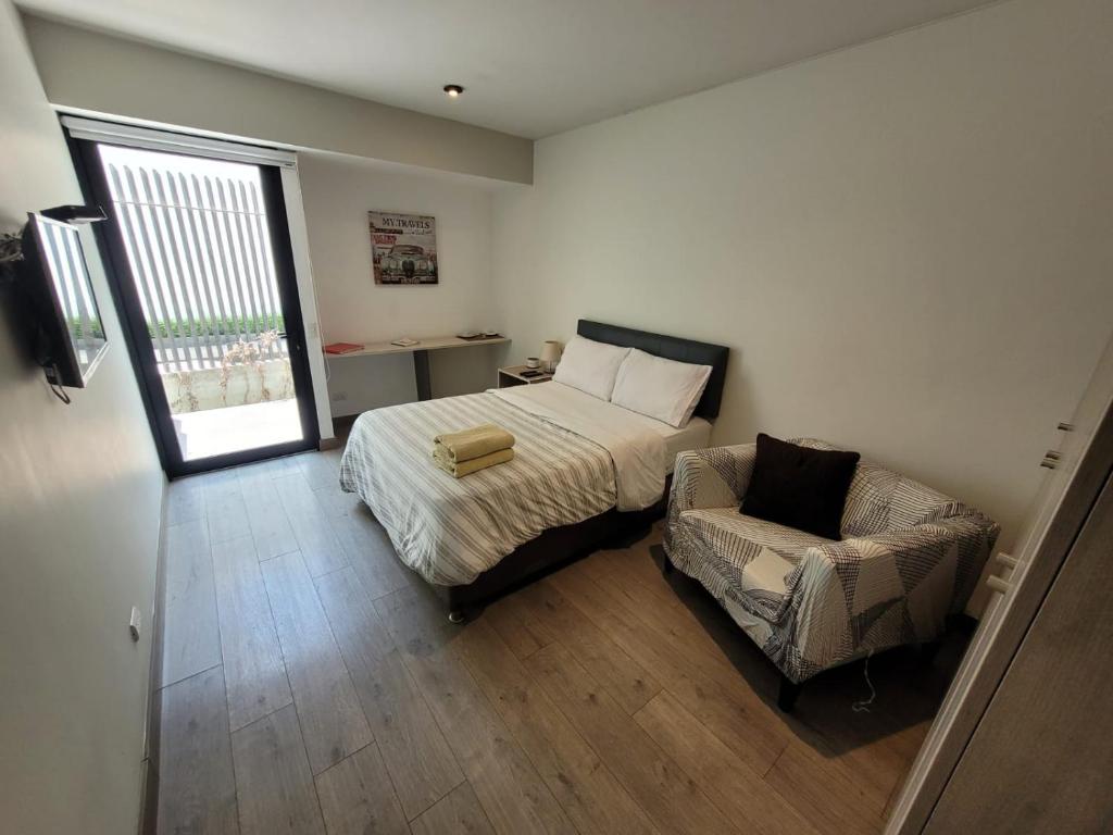 1 dormitorio con 1 cama y 1 silla en Espacio Luxury Apartments “Edificio Boutique B51”, en Lima
