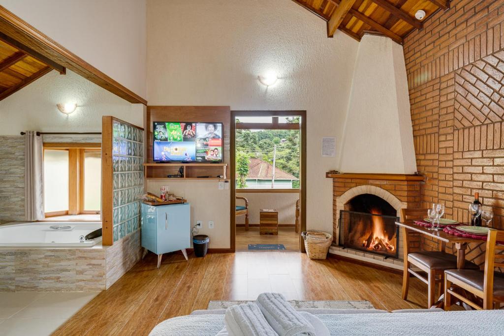 a living room with a fireplace and a tv at Pousada Jardim Monte Verde in Monte Verde