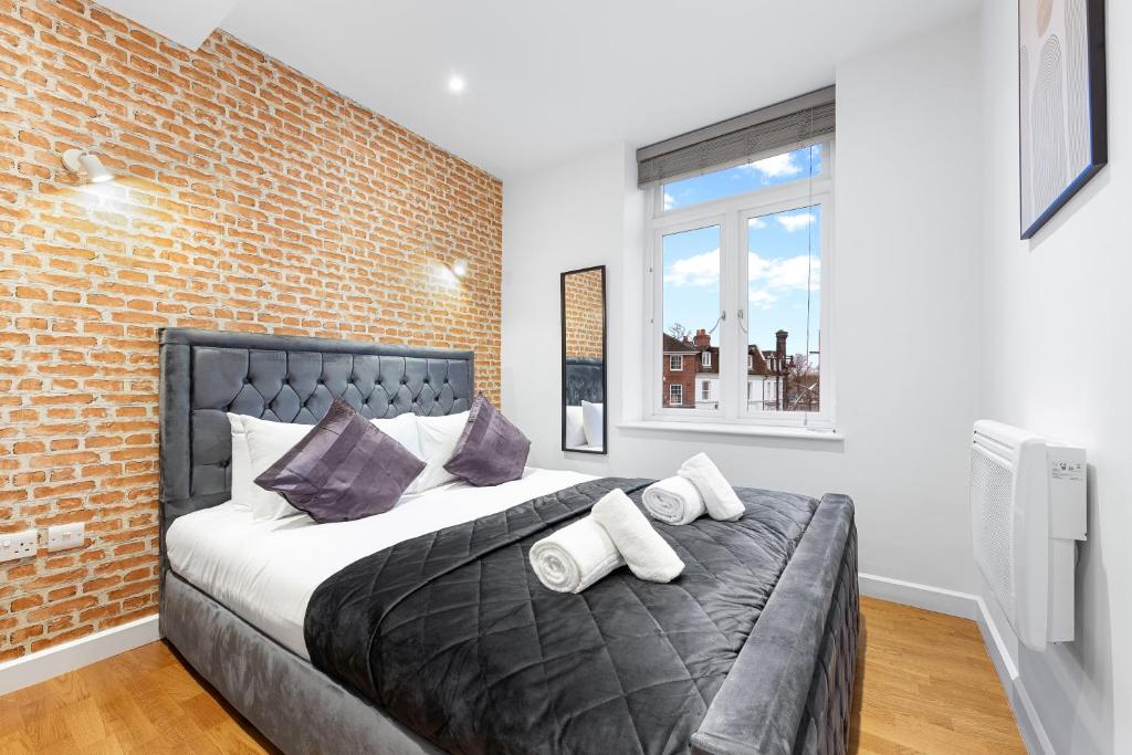 ロンドンにあるStylish One Bedroom Flat - Near Heathrow, Windsor Castle, Thorpe Park - Staines London TW18のレンガの壁のベッドルーム1室(大型ベッド1台付)