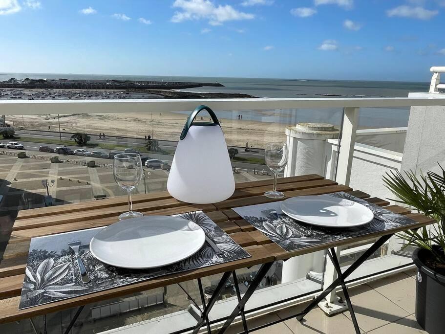 une table avec des assiettes et des verres à vin sur un balcon dans l'établissement Studio Côte&Plage, vue mer panoramique, à Pornichet
