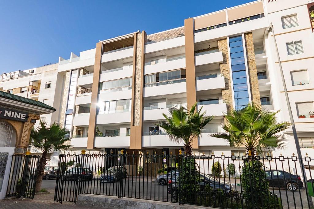 un bâtiment blanc avec des palmiers devant lui dans l'établissement Charmant appartement près de TGV, à Kenitra