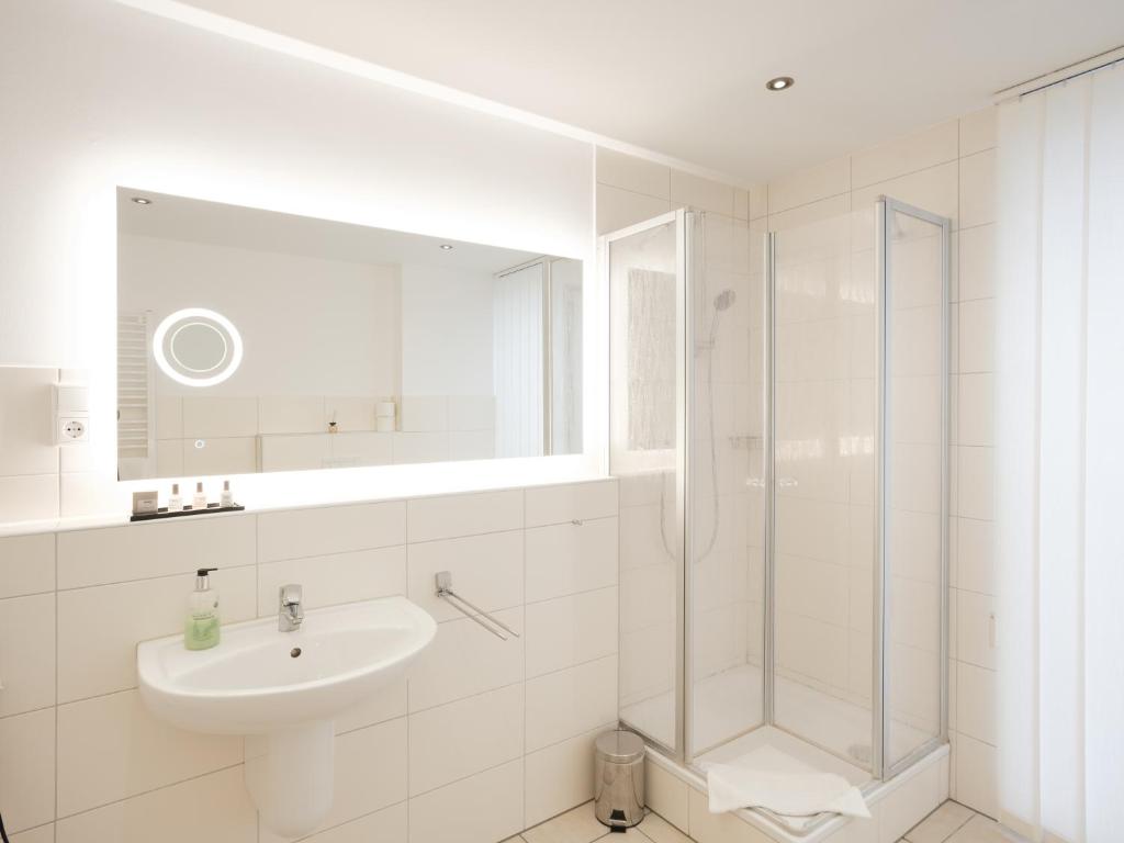 a white bathroom with a sink and a shower at city boarding lippstadt in Lippstadt