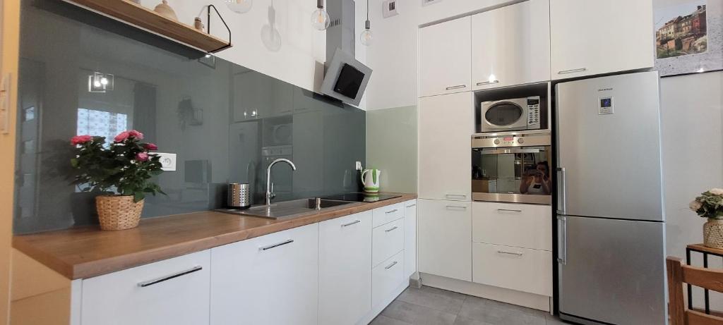a kitchen with white cabinets and a stainless steel refrigerator at Apartament 39 in Lublin