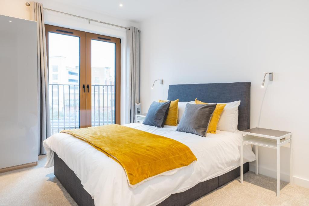 a bedroom with a large bed with a yellow blanket at St Albans 1 Bed Luxury City Apartment, 5 mins walk to Train & Allocated Parking in St. Albans