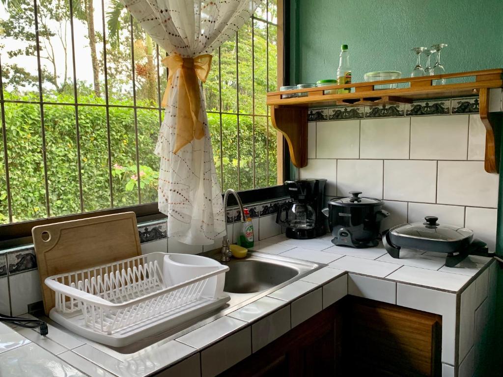 encimera de cocina con fregadero y ventana en Casita el jardin en Bijagua