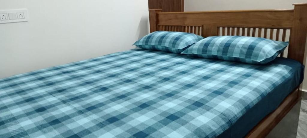 a bed with blue plaid sheets and two pillows at Arasu Homestay in Antarasante