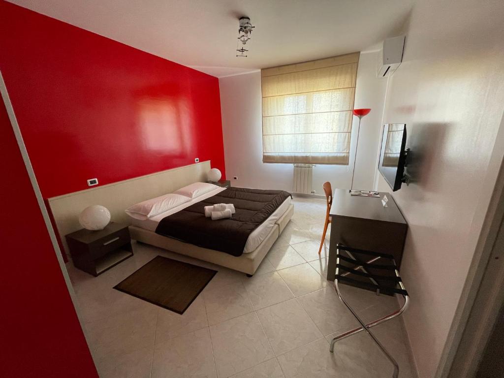 - une chambre avec des murs rouges, un lit et une table dans l'établissement B&B Elia's, à Cagliari