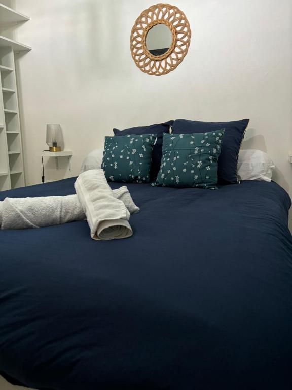 una cama azul con sábanas y almohadas azules y un espejo en Appartement Rubis, en Cayenne