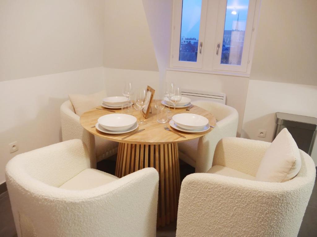 a dining room table with white chairs and a wooden table at Magnifique cocon in Amiens