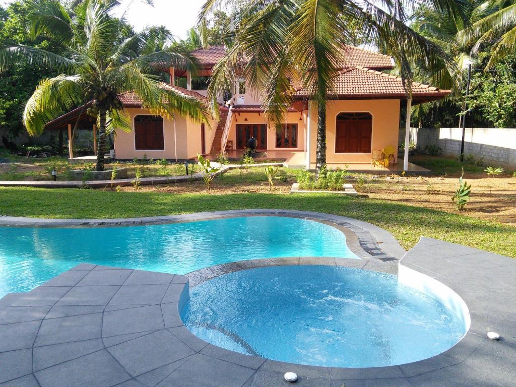 a swimming pool in front of a house at King Coconut Lodge in Habaraduwa