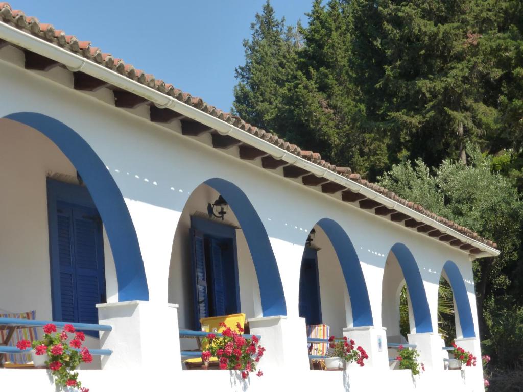 a white building with blue arches and flowers on it at Spiti Melianou in Agios Georgios Pagon