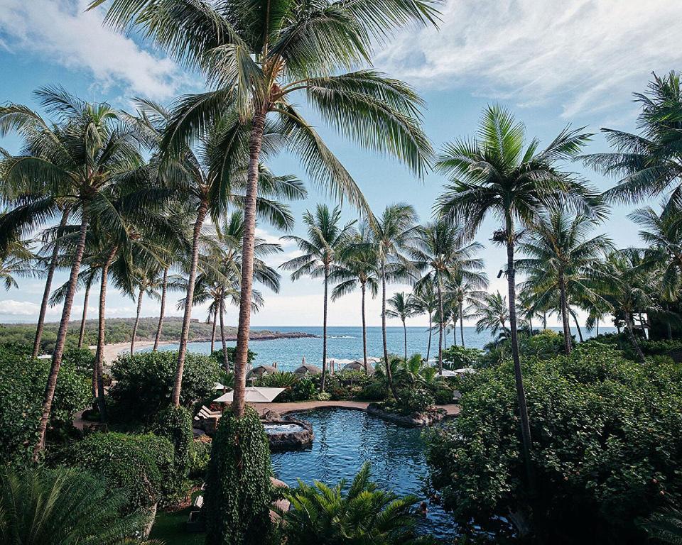 ein Resort mit einem Pool, Palmen und dem Meer in der Unterkunft Four Seasons Resort Lana'i in Lanai City