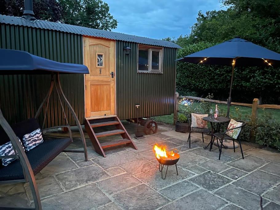 a backyard with a fire pit and a shed at Forest View Shepherd Hut in Ewhurst