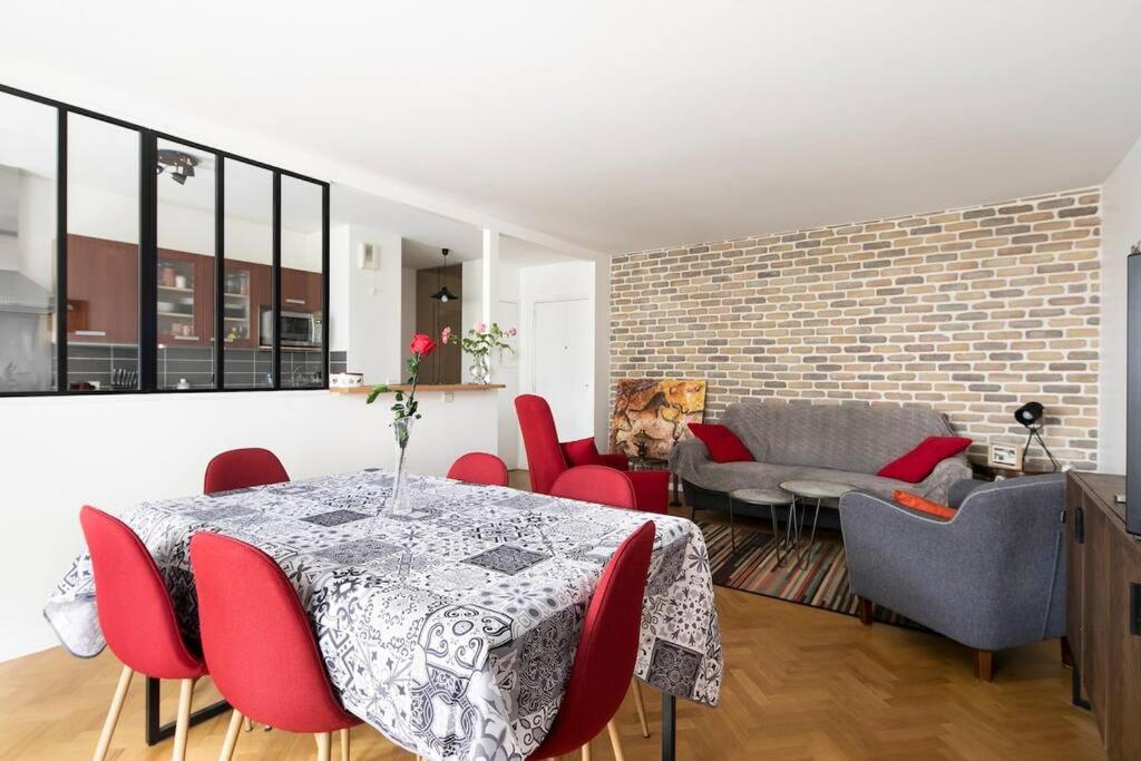 sala de estar con mesa, sillas y pared de ladrillo en Charmant Appartement - Portes de Paris, en Charenton-le-Pont