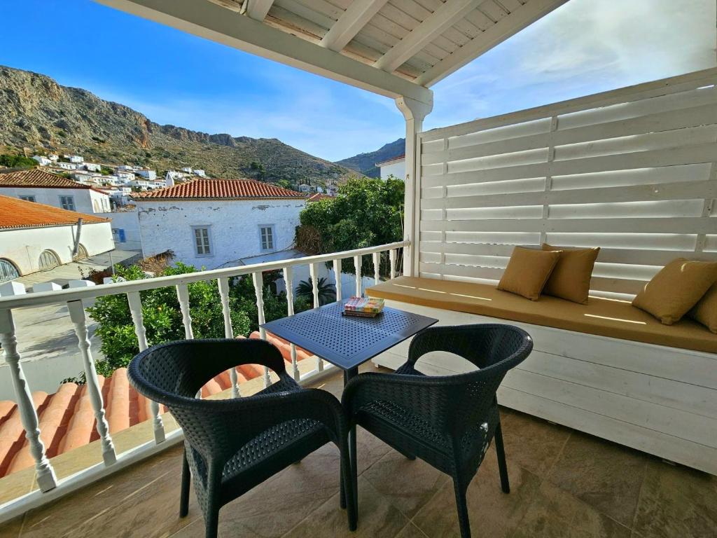 a balcony with a table and chairs and a bench at Kirki Hydra in Hydra