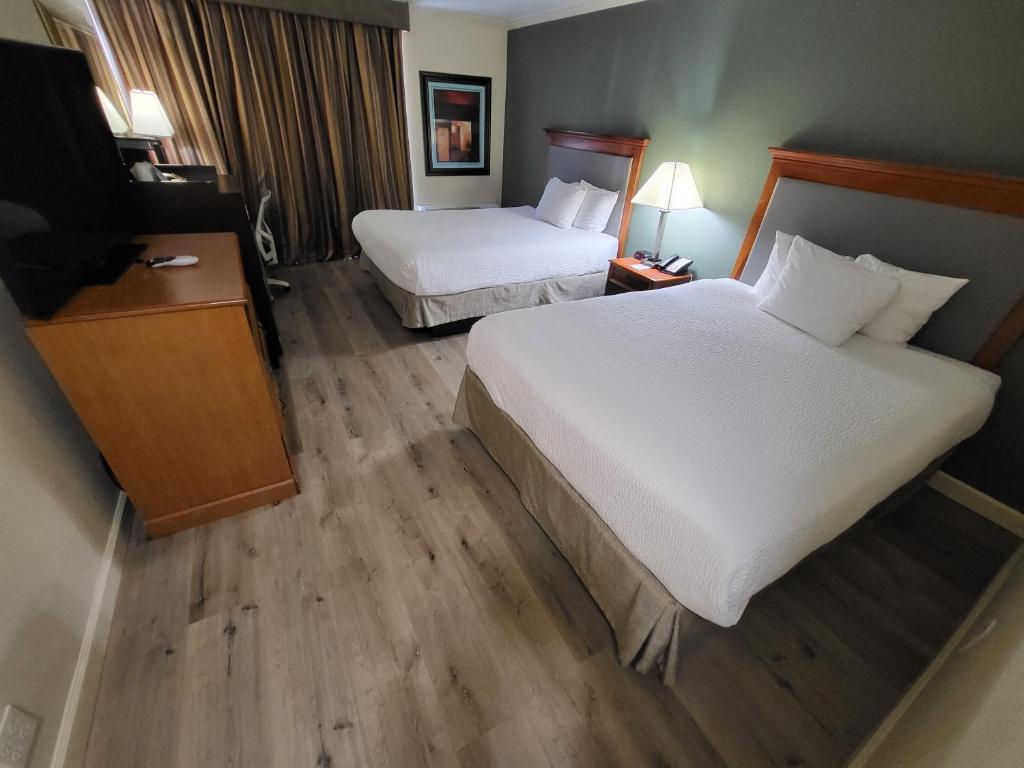 a hotel room with two beds and a flat screen tv at Ramada by Wyndham Houston Intercontinental Airport East in Humble