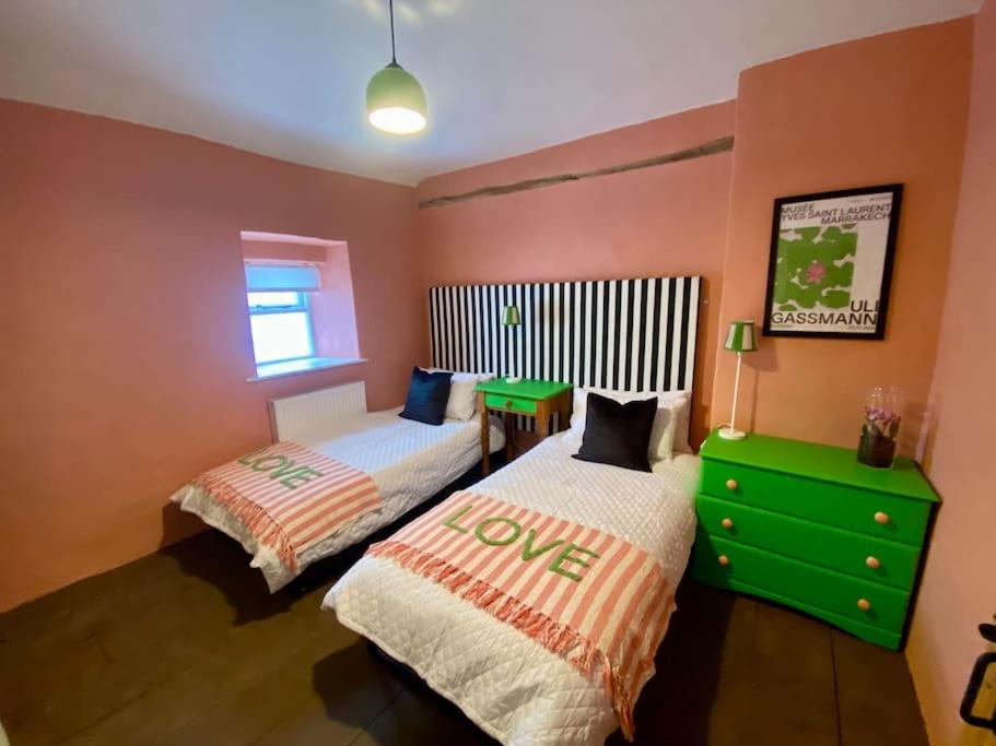 1 dormitorio con 2 camas y vestidor verde en The Old Hat Shop, en Cromford