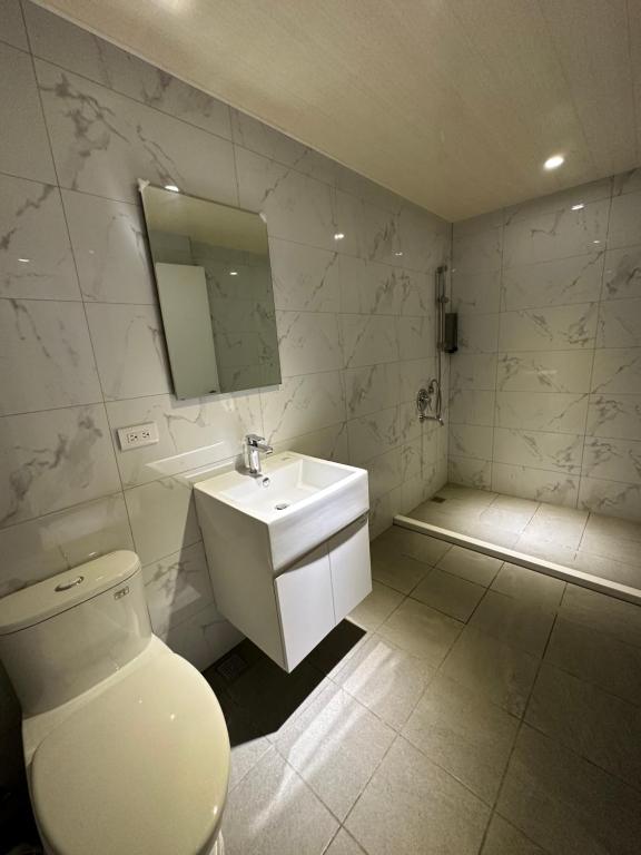 a white bathroom with a toilet and a sink at Tie Dao Hotel in Tainan
