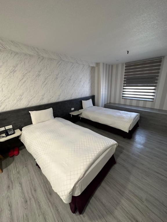 a bedroom with two beds and a window at Tie Dao Hotel in Tainan