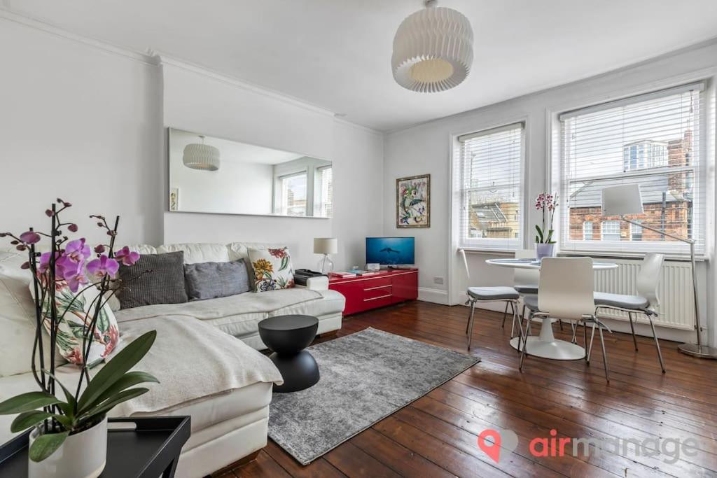 ein Wohnzimmer mit einem Sofa und einem Tisch in der Unterkunft West Kensington 2Bed Flat in London