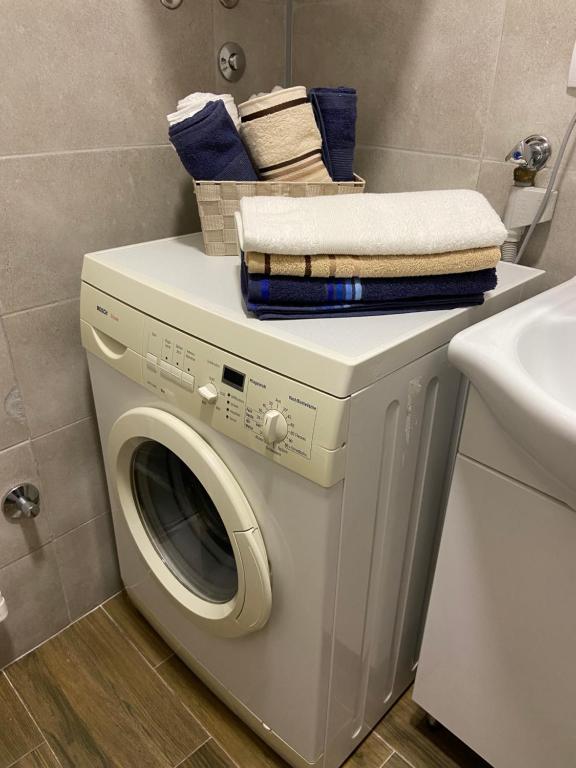 a white washing machine in a bathroom with a sink at Kula Dream apartment in Kula