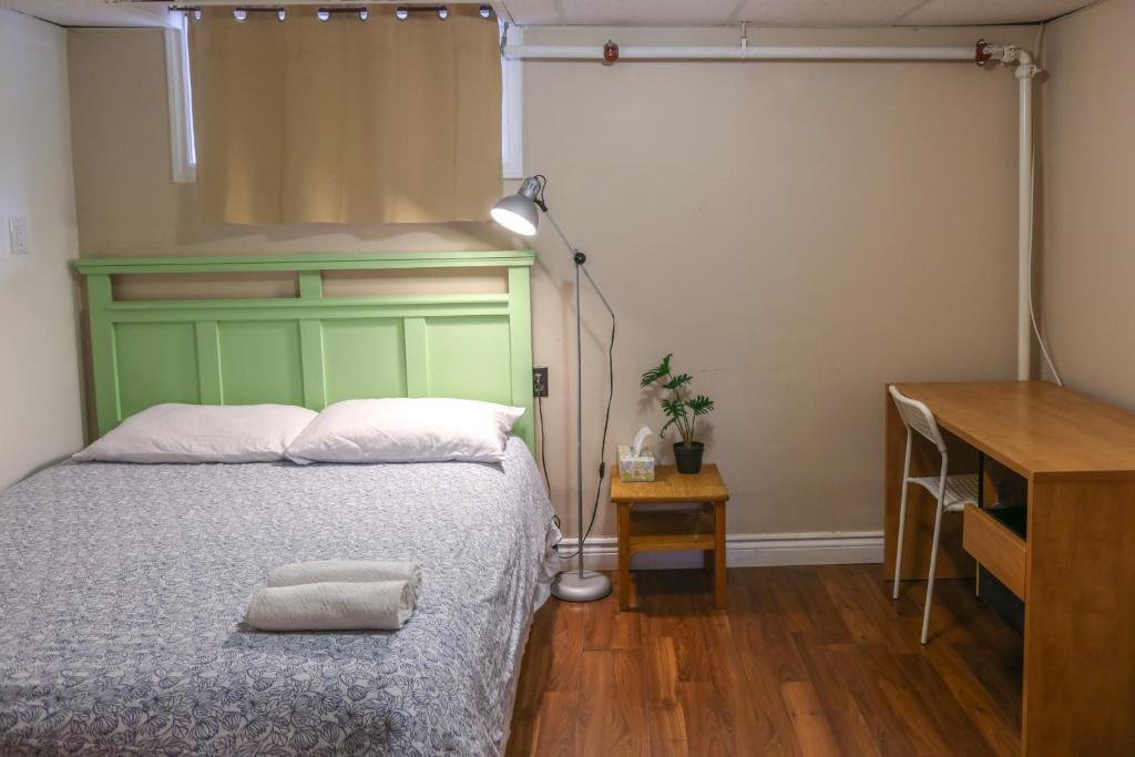 a bedroom with a bed with a green headboard and a table at Cozy stay close to Merivale in Ottawa