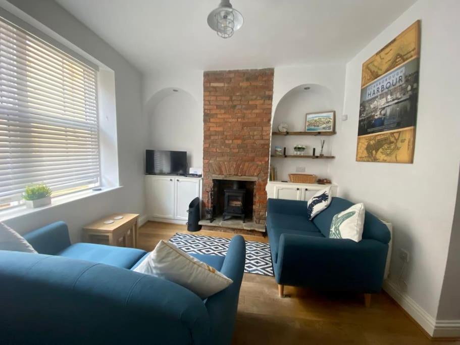 a living room with two blue couches and a fireplace at Harbour Hideaway, Scarborough. Old Town in Scarborough
