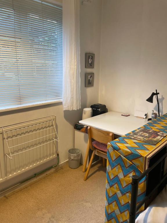a bedroom with a bed and a table and a window at Little Temple in Ladywell in London