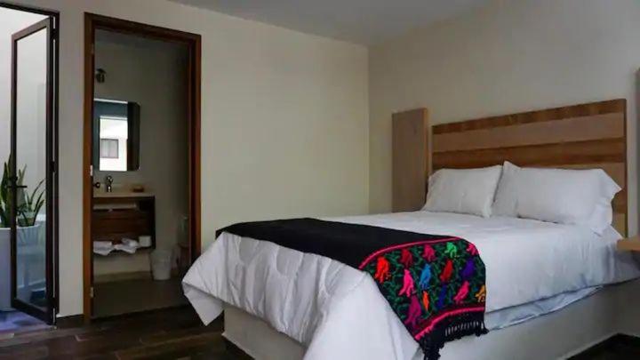 a bedroom with a large white bed and a mirror at El Ciruelo in Teziutlán