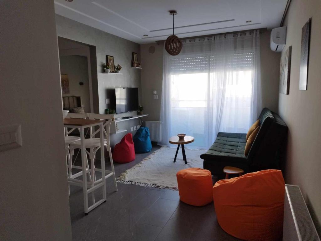 a small living room with a couch and a kitchen at Coquette Appartement in Boumhel El Bassatine